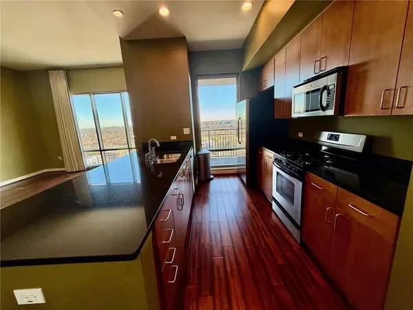 a kitchen with stainless steel appliances granite countertop a stove a refrigerator a sink and dishwasher with wooden floor