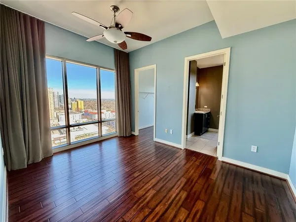 a view of an empty room with wooden floor and a window