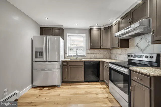 a kitchen with granite countertop a refrigerator and a stove top oven