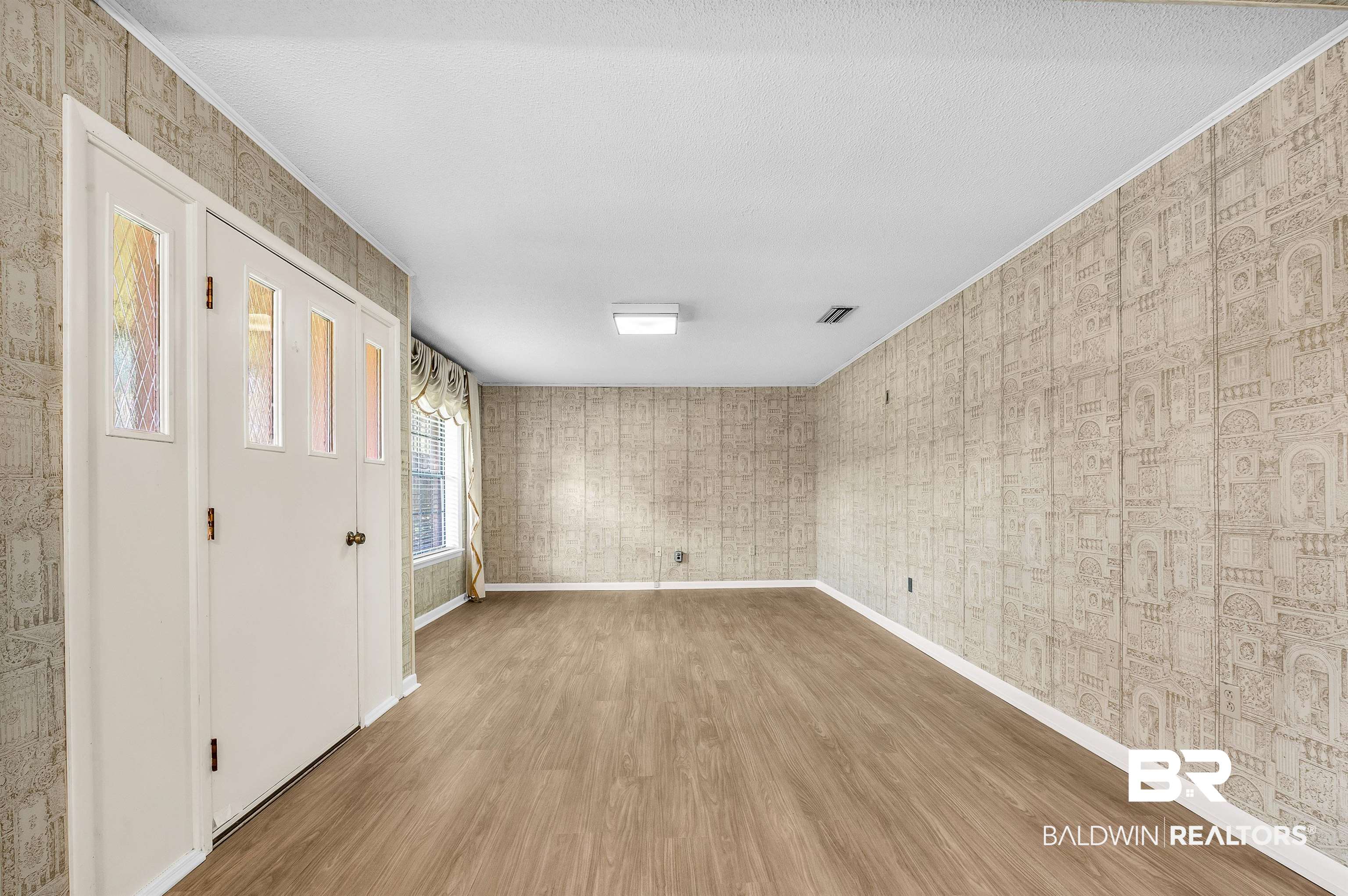 610 East Walker Avenue Foley, AL 36535 - Photo 11 of 38 Unfurnished room with wood finished floors, ornamental molding, and wallpapered walls