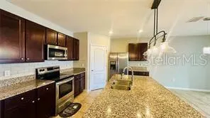 a kitchen with granite countertop a stove refrigerator and microwave