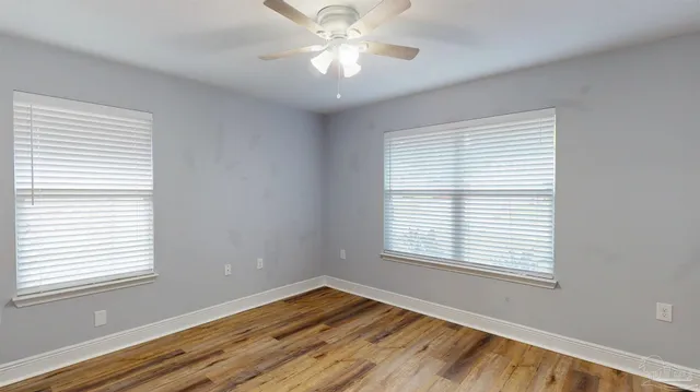 an empty room with wooden floor closet and windows
