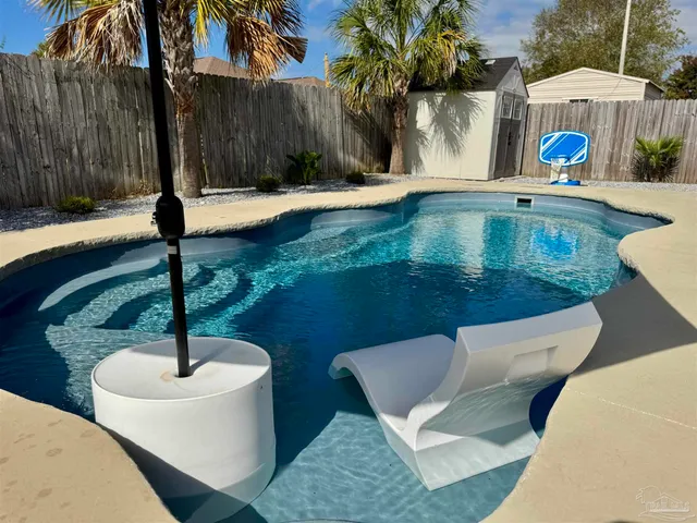 a swimming pool with a table and chairs under an umbrella