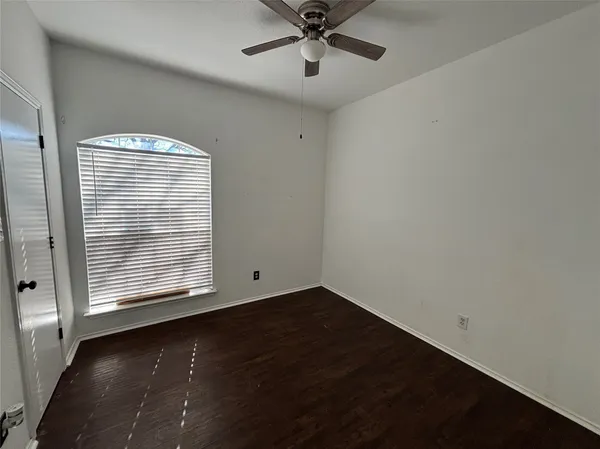 an empty room with wooden floor fan and windows