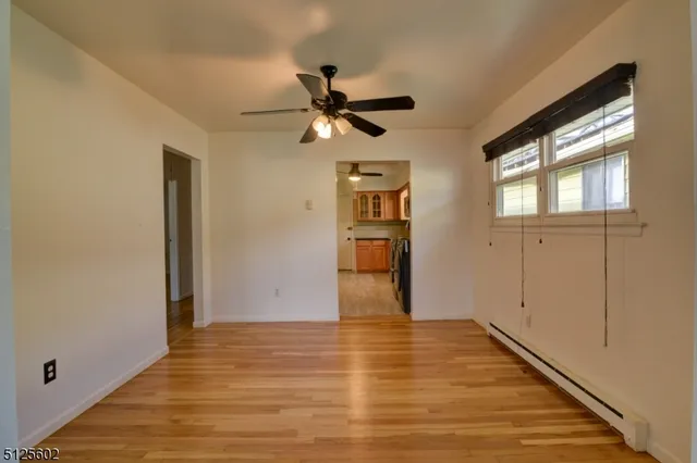 a view of empty room with wooden floor and fan