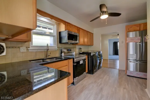 a kitchen with stainless steel appliances granite countertop a refrigerator a stove top oven a sink and dishwasher