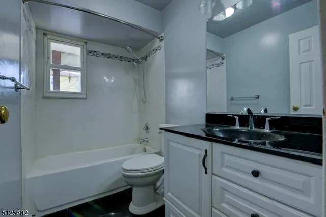 a bathroom with a granite countertop sink a toilet a mirror and bathtub