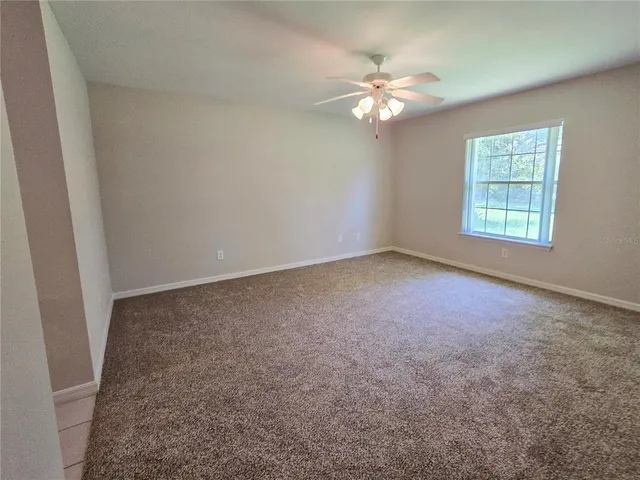 an empty room with windows and chandelier fan