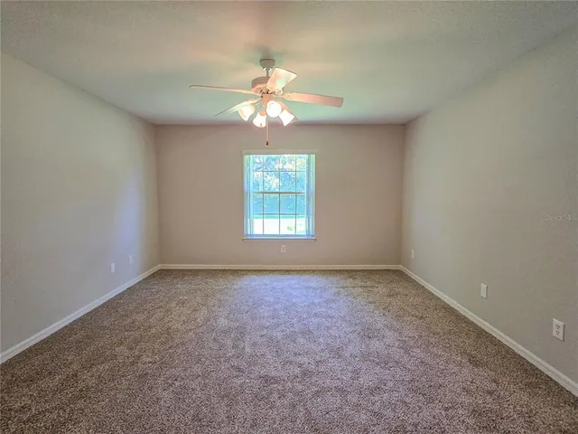 an empty room with windows and chandelier fan