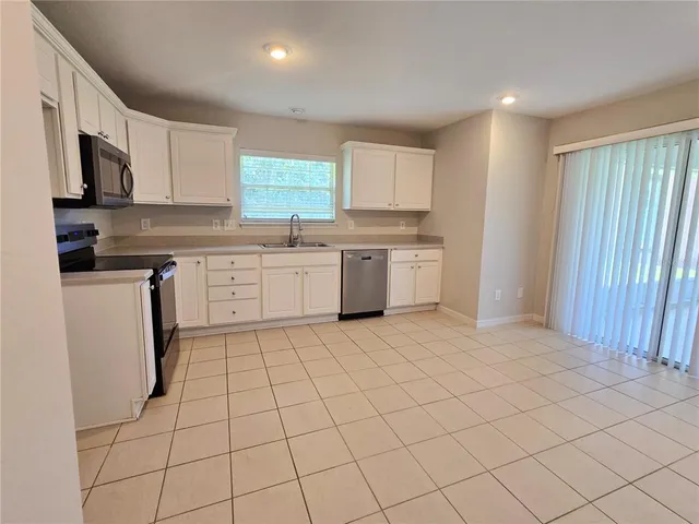 a large white kitchen with a sink window and cabinets