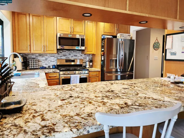a kitchen with kitchen island granite countertop a stove top oven microwave and refrigerator