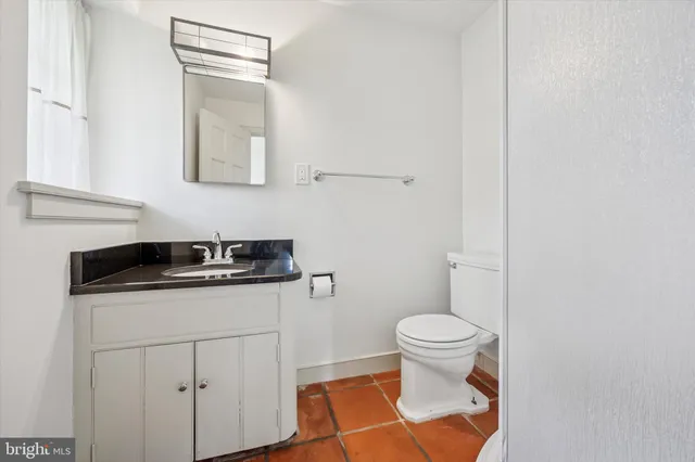 a bathroom with a granite countertop sink a toilet and a mirror