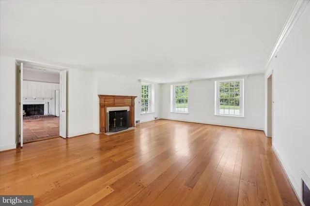 an empty room with wooden floor fireplace and windows