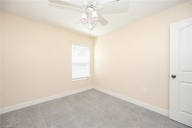 an empty room with a chandelier fan and windows