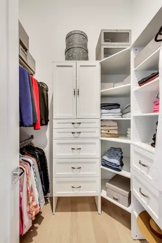 a view of walk in closet with clothes and shoes