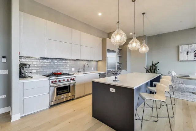 a kitchen with kitchen island a stove a table and chairs in it