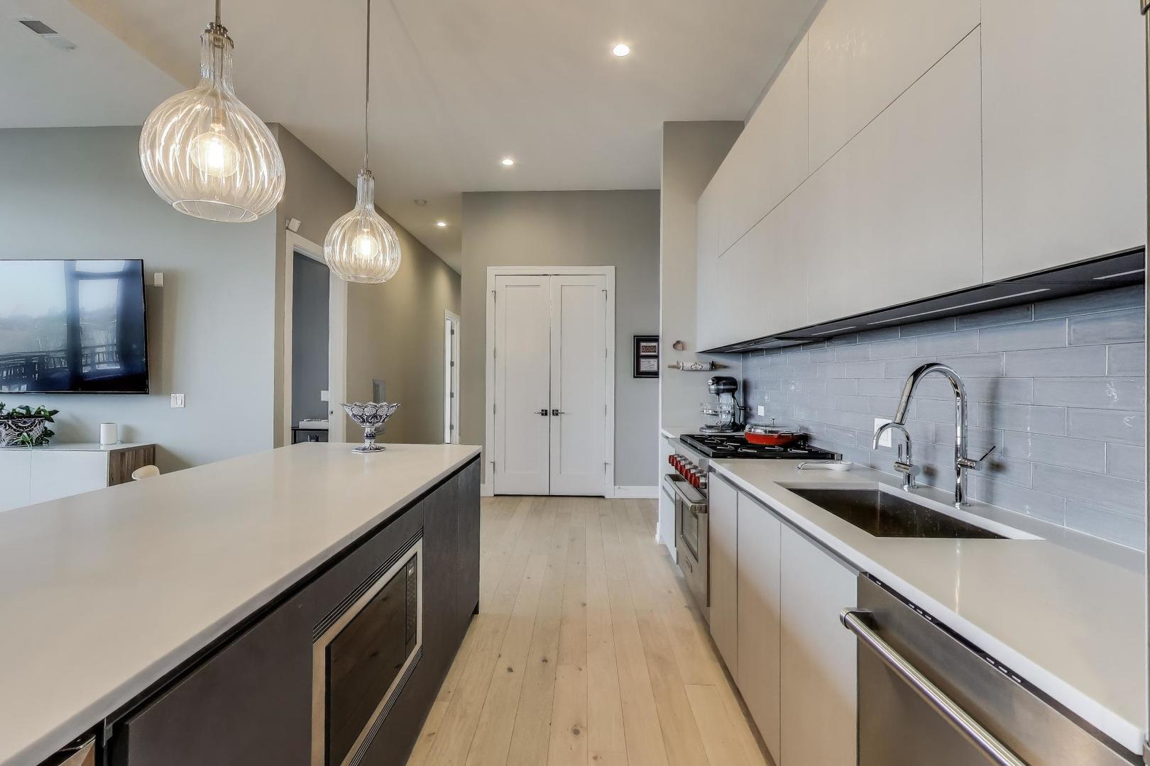 2405 West Iowa Street, Unit 405 Chicago, IL 60622 - Photo 7 of 35 a kitchen with a sink dishwasher a stove and a refrigerator with wooden floor