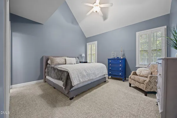 a bedroom with a bed couch and windows