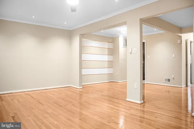 a view of an empty room with wooden floor and closet