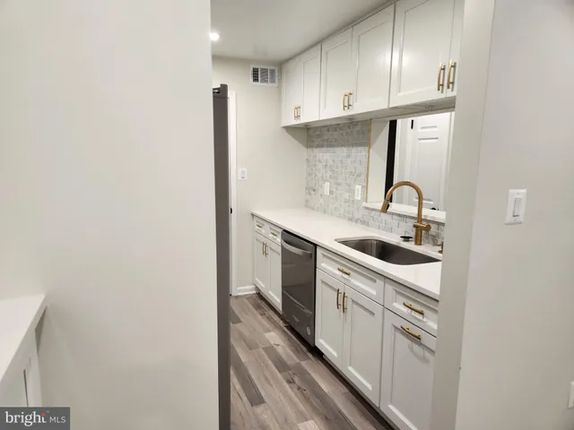 a view of a sink and dishwasher with wooden floor