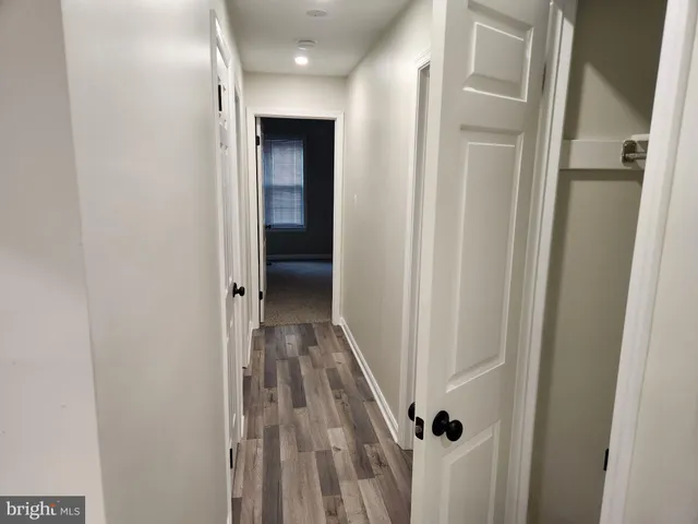 a view of a hallway with wooden floor and a bathroom