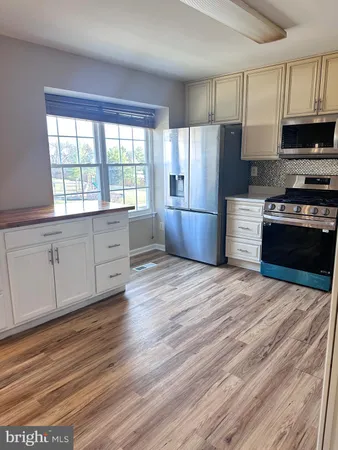 a kitchen with stainless steel appliances granite countertop a stove a refrigerator a sink a microwave oven with cabinets and wooden floor
