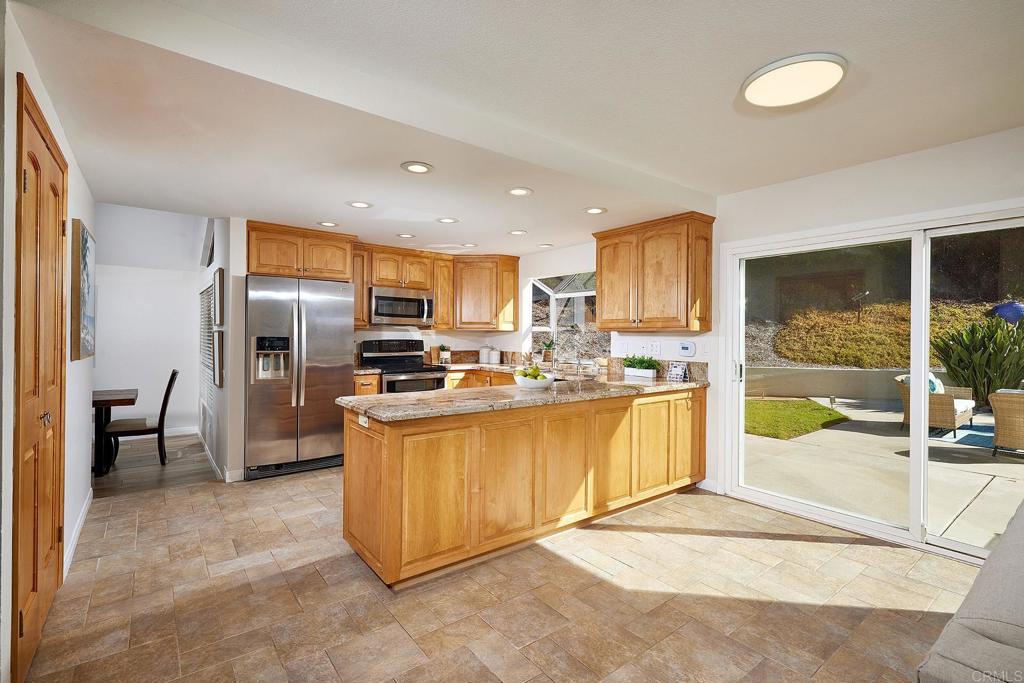 2107 Meadowgreen Court Encinitas, CA 92024 - Photo 13 of 49 a large kitchen with stainless steel appliances kitchen island granite countertop a refrigerator and a sink