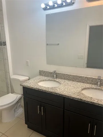 a bathroom with a granite countertop sink a toilet and a mirror