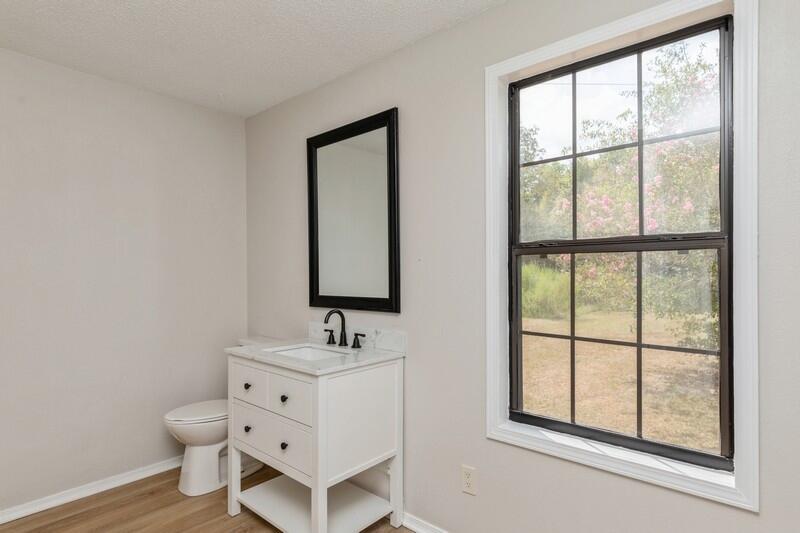 5867 Oak Hill Road Crestview, FL 32536 - Photo 28 of 33 a bathroom with a toilet sink a mirror and next to a window