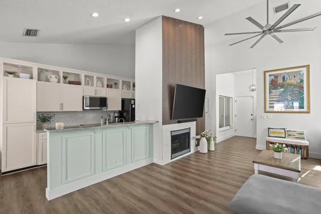 a large open kitchen with stainless steel appliances refrigerator a dining table and chairs with wooden floor