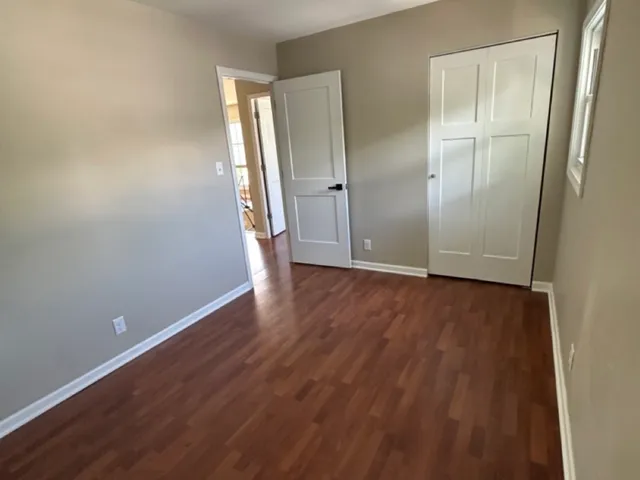 an empty room with wooden floor and mirror