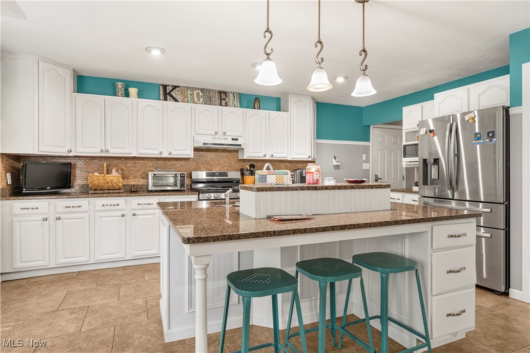 155 Ridgewood Boulevard Belpre, OH 45714 - Photo 26 of 49 Kitchen featuring backsplash, stainless steel appliances, hanging light fixtures, and white cabinetry