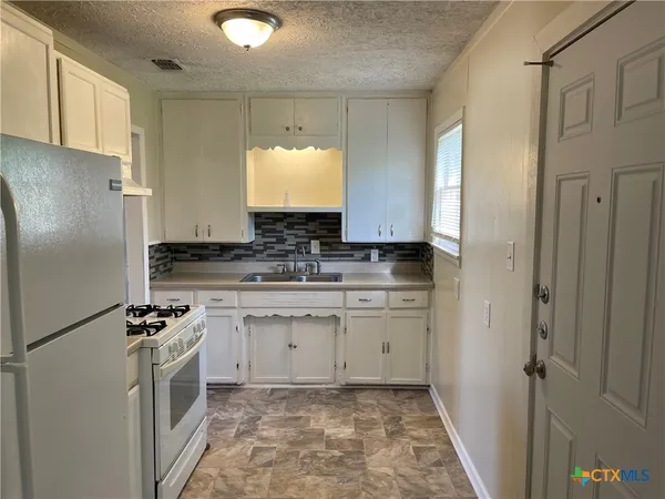 a kitchen with white cabinets and refrigerator