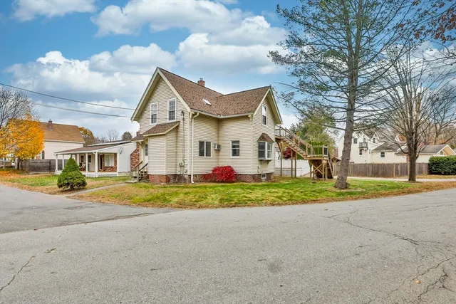 a view of a white house next to a yard and road