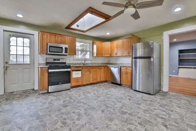 a kitchen with stainless steel appliances granite countertop a refrigerator a stove a sink and a microwave
