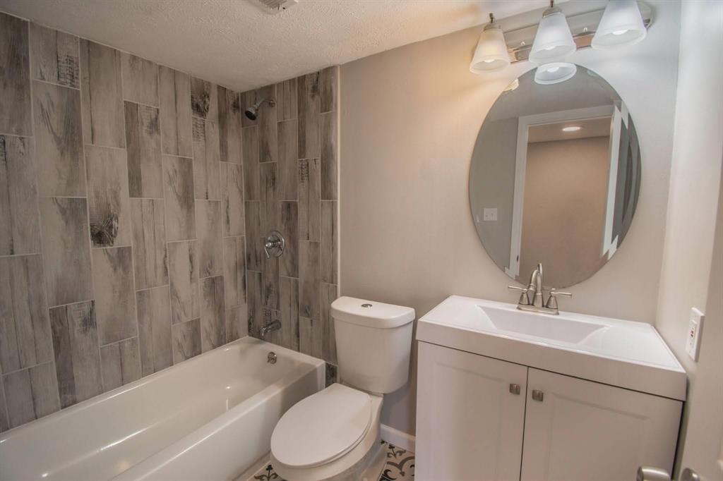 3825 Hackberry Lane Bedford, TX 76021 - Photo 12 of 24 a bathroom with a toilet a sink a mirror a bathtub and shower