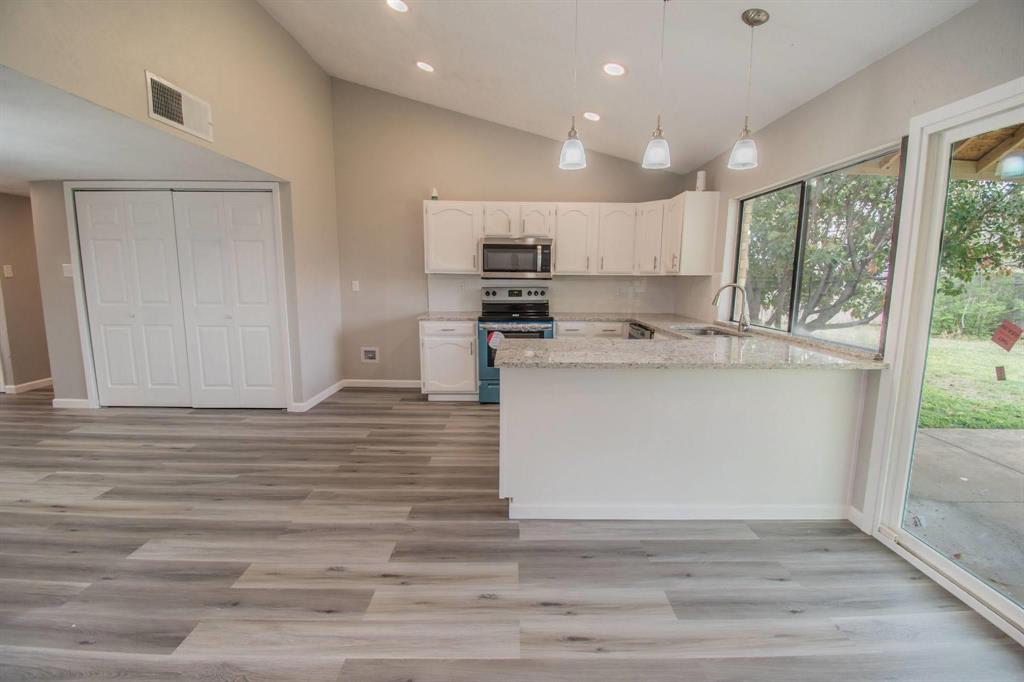 3825 Hackberry Lane Bedford, TX 76021 - Photo 4 of 24 a kitchen with stainless steel appliances granite countertop a sink a stove a refrigerator and white cabinets