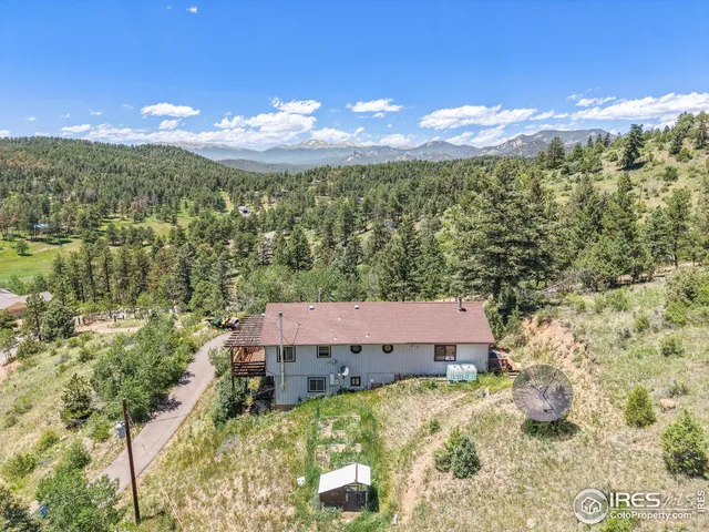 an aerial view of a house with yard and trees in the background