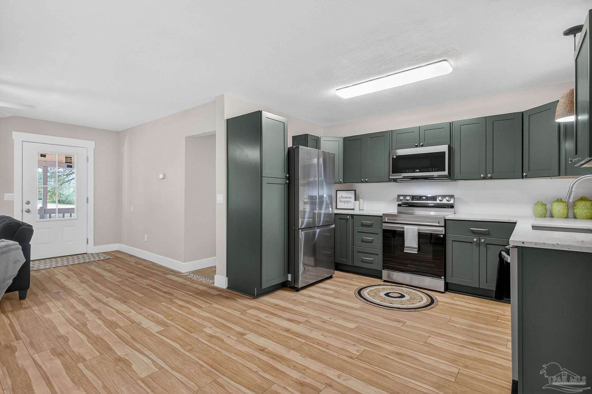4771 Carl Booker Road Milton, FL 32583 - Photo 23 of 65 a area with stainless steel appliances a refrigerator and a stove top oven