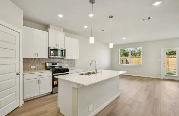 a kitchen that has a sink a stove top oven a counter space and cabinets