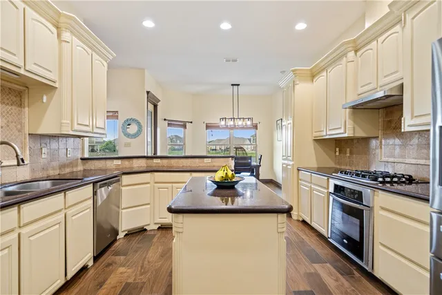 a kitchen with granite countertop a sink stove and cabinets