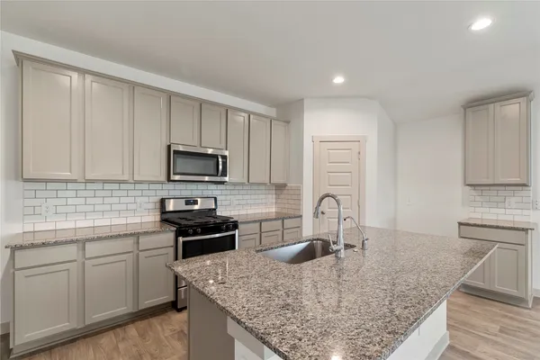 a kitchen with kitchen island granite countertop a sink a stove counter space and cabinets