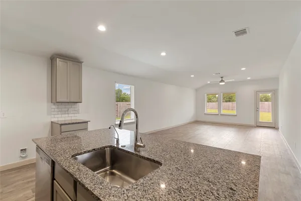 a kitchen with granite countertop a sink and a toilet