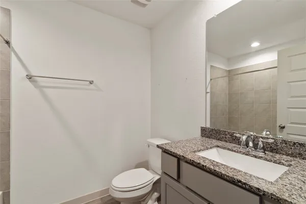 a bathroom with a granite countertop sink a toilet a mirror and shower