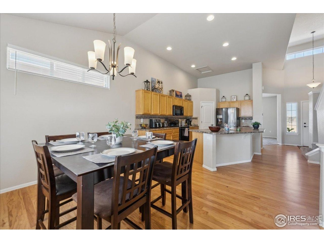 623 Gore Range Drive Severance, CO 80550 - Photo 6 of 36 a view of a dining room and livingroom with furniture wooden floor a rug a painting and a chandelier
