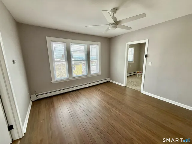a view of an empty room with wooden floor and a window