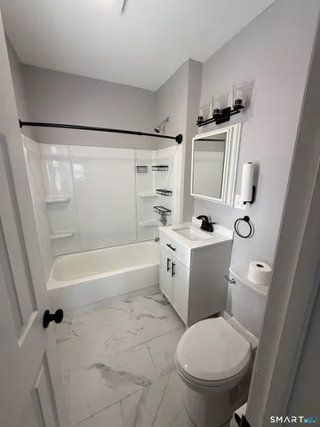 a white toilet sitting next to a bath tub