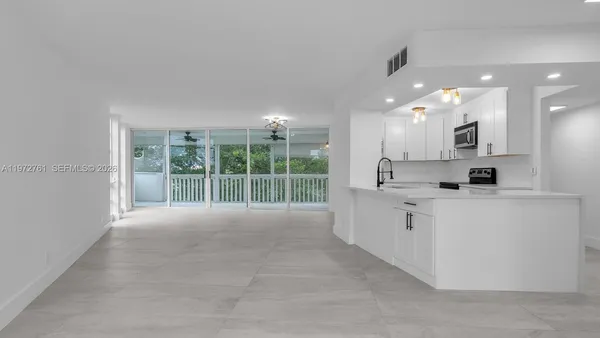 a large white kitchen with large windows and white cabinets