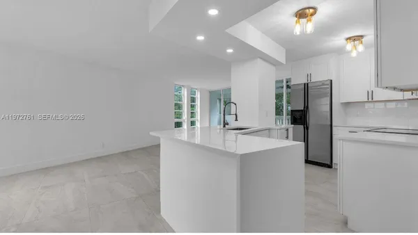 a kitchen with stainless steel appliances a refrigerator sink and white cabinets