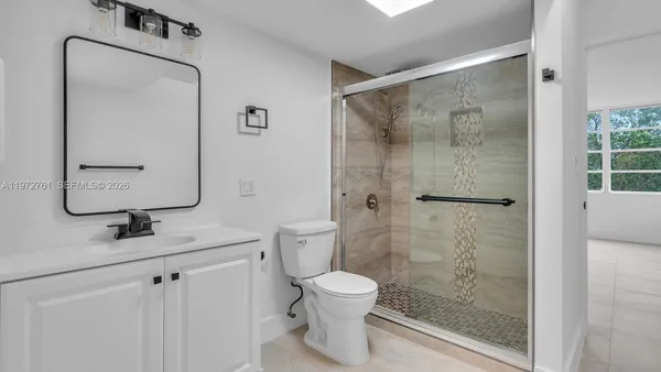 a bathroom with a shower sink vanity and toilet